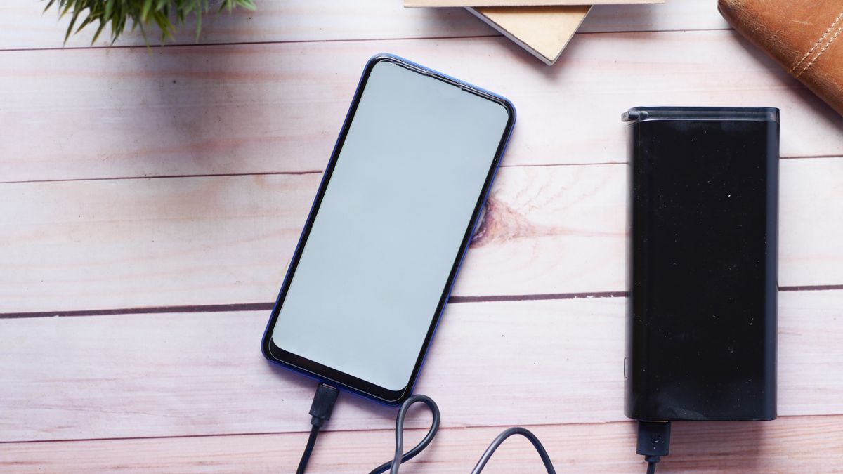 木のデスクの上でモバイルバッテリーからスマートフォンを充電している様子